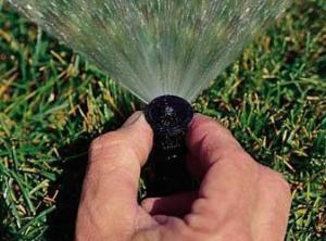 a Mesquite sprinkler tech hand adjusts a spray head